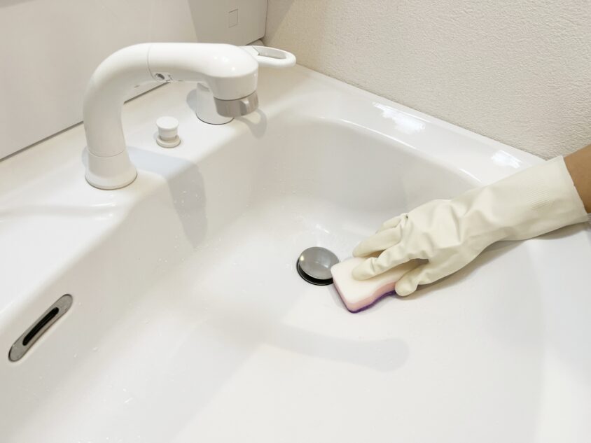 スポンジで洗面台排水口付近を掃除する様子