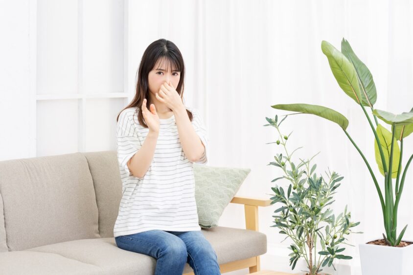 鼻をつまんでソファに座っている若い女性
