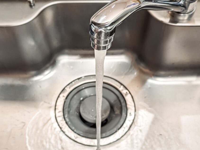キッチンのシンクに水を流す様子