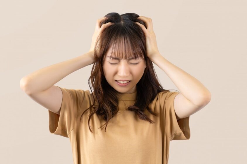 頭をかかえる若い女性