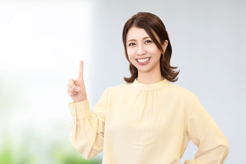 笑顔で人差し指を立てる若い女性