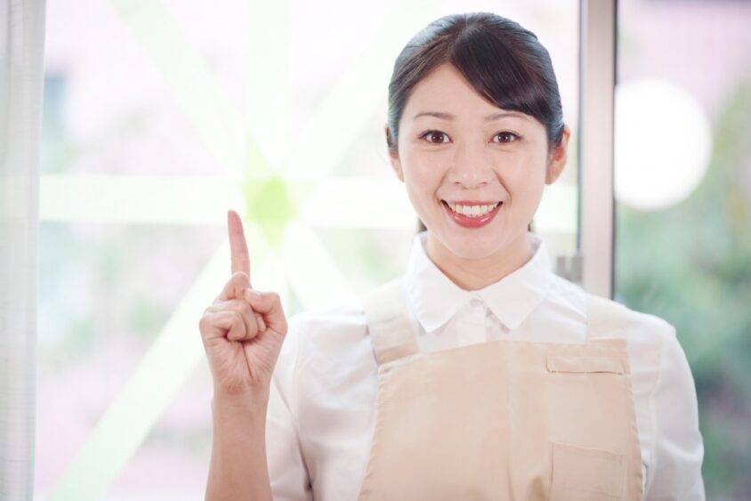 人差し指を立てる笑顔の女性