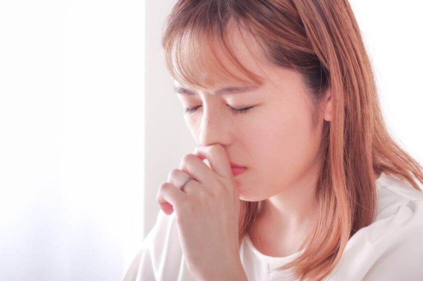 鼻に手をあてている若い女性