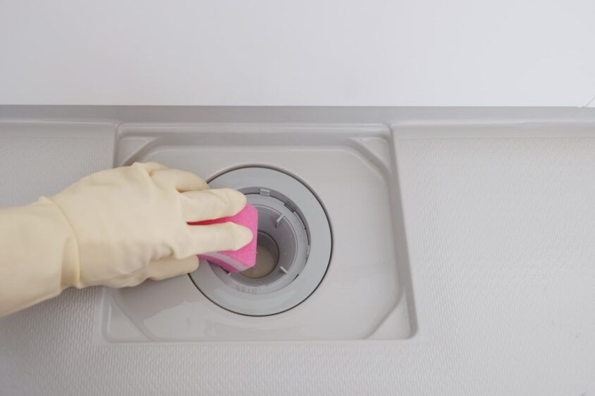 スポンジでお風呂の排水口を掃除する様子